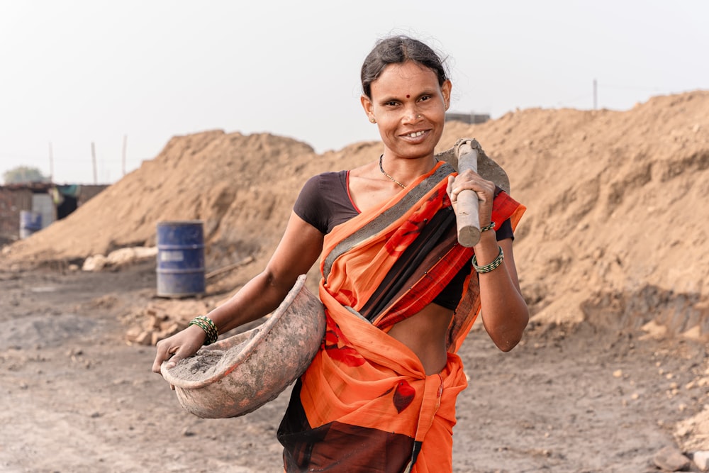 uma mulher segurando uma cobra em um campo de terra