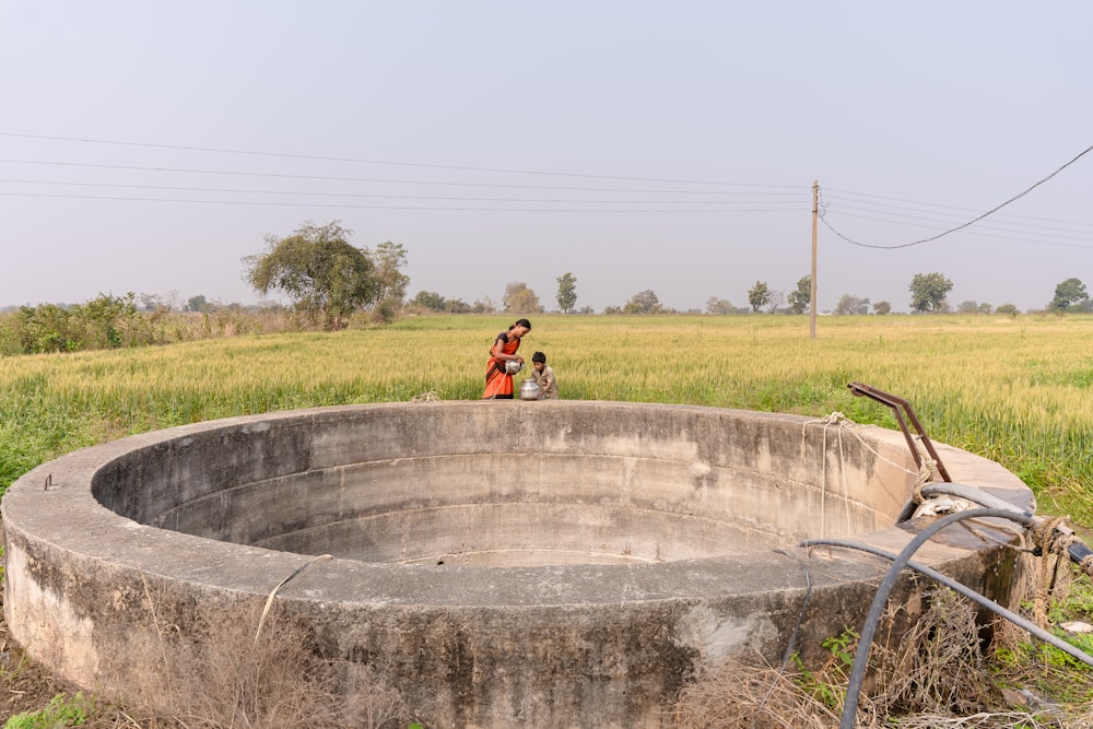 a woman in a red dress standing next to a large concrete bowl