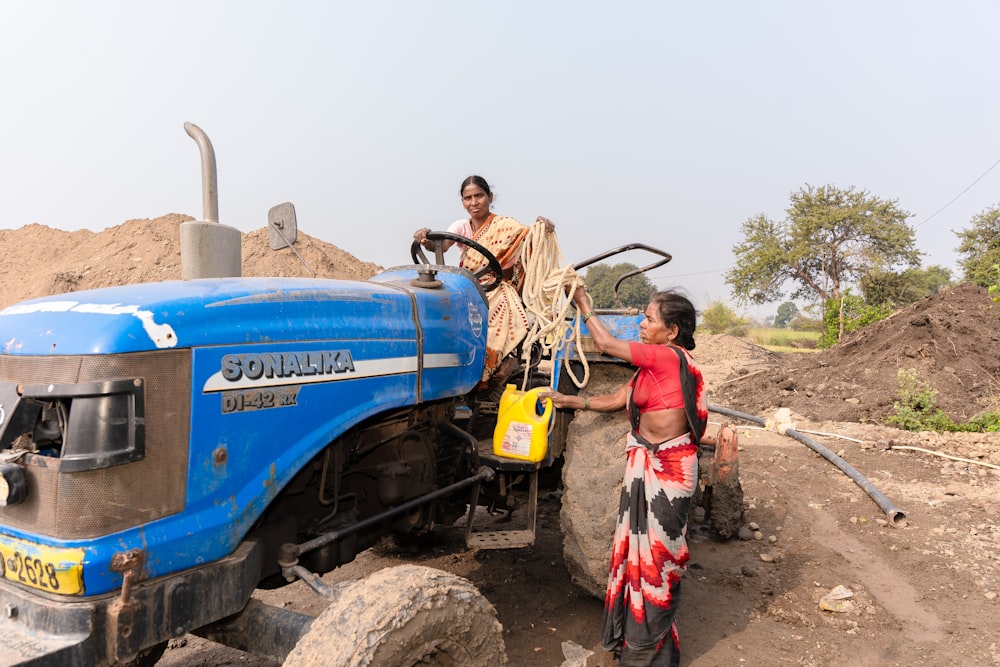 a woman standing next to a blue tractor