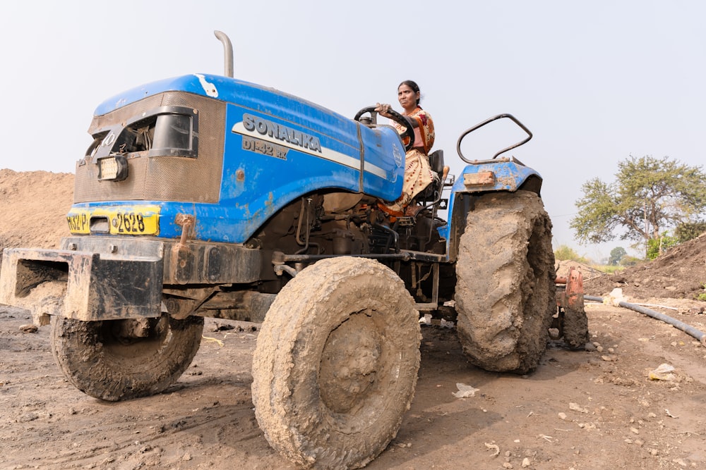 a man riding on the back of a blue tractor