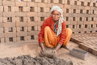 a woman kneeling down next to a pile of bricks