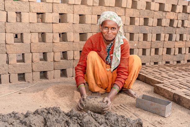 a woman kneeling down next to a pile of bricks