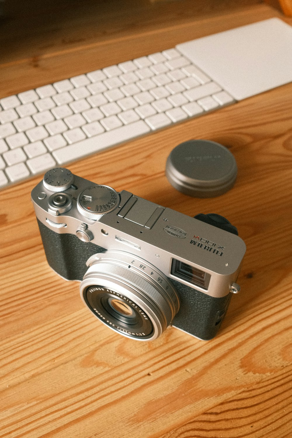 a camera sitting on top of a wooden table next to a keyboard