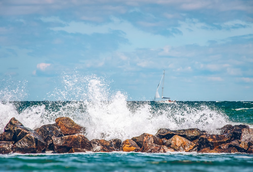 a sailboat in the ocean near a rocky shore