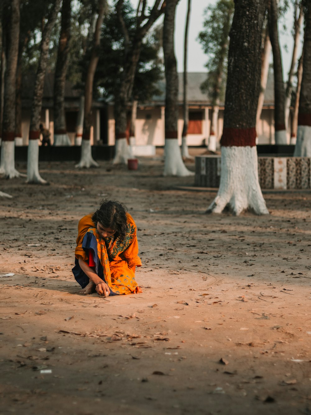 a person sitting on the ground in the middle of a park