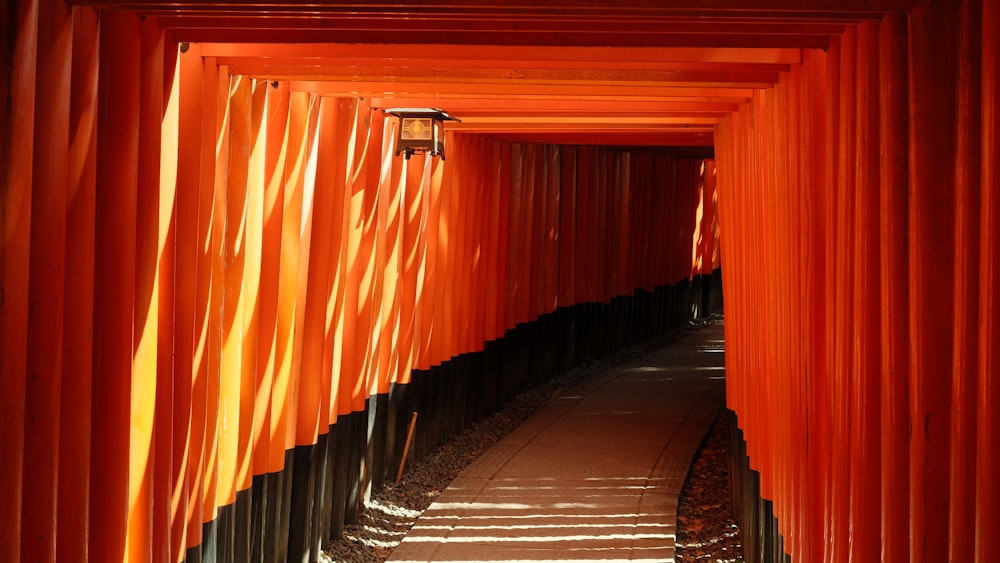 uma passarela ladeada por portões laranjas que levam à distância