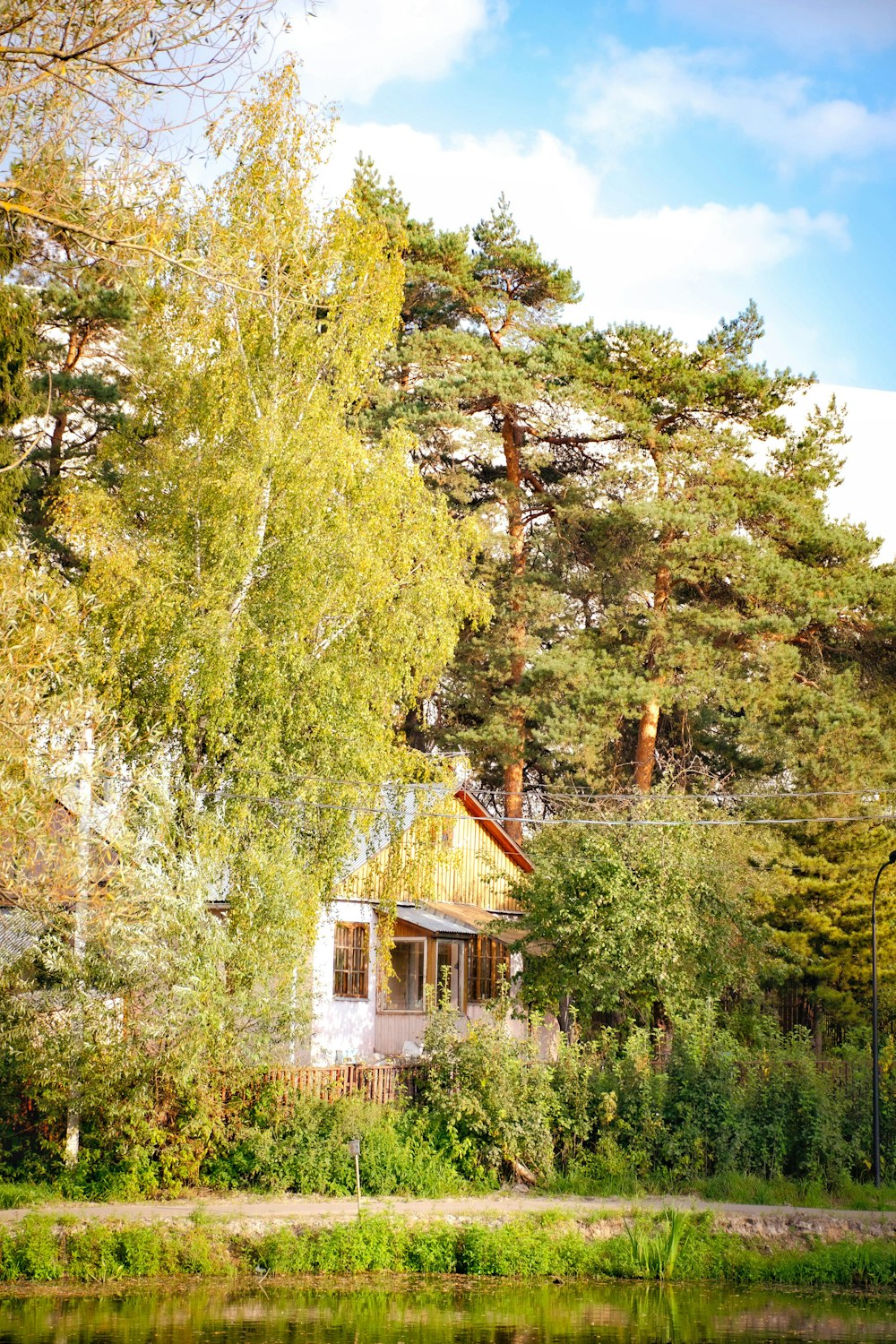 a house sitting next to a lake surrounded by trees