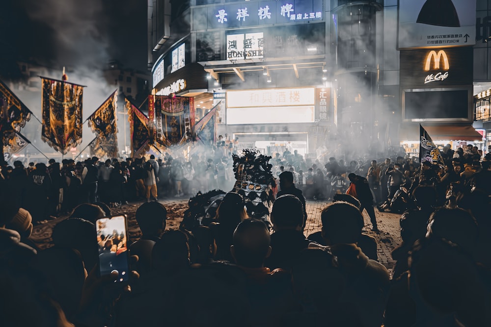 a crowd of people standing around a street at night