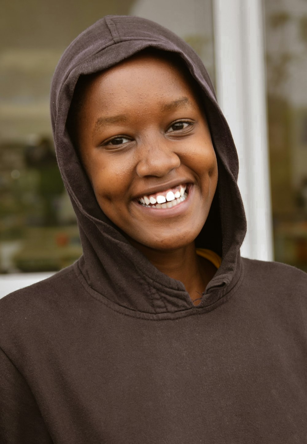 a smiling young woman wearing a brown hoodie