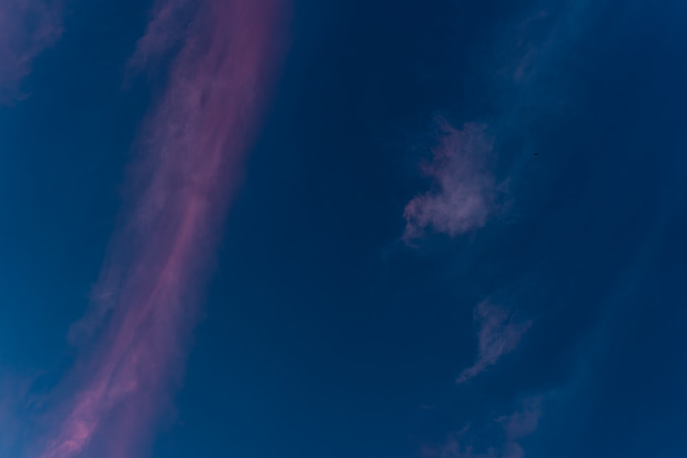 un avión volando en el cielo azul con nubes