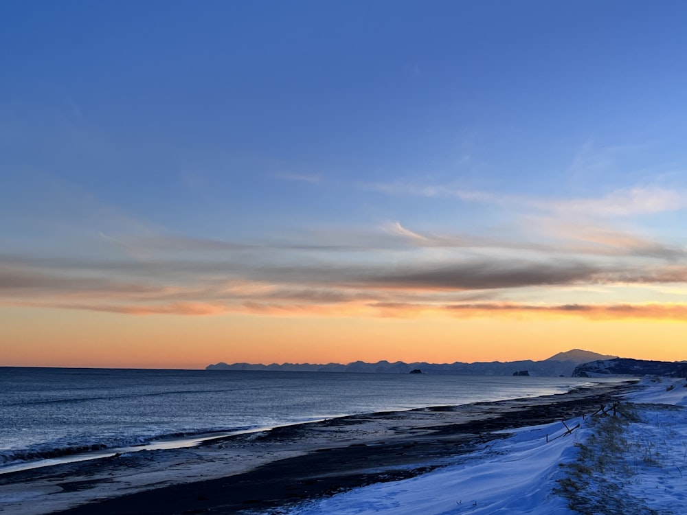 the sun is setting over the ocean and a beach