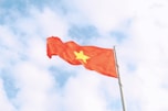 a red flag with a yellow star flying in the sky