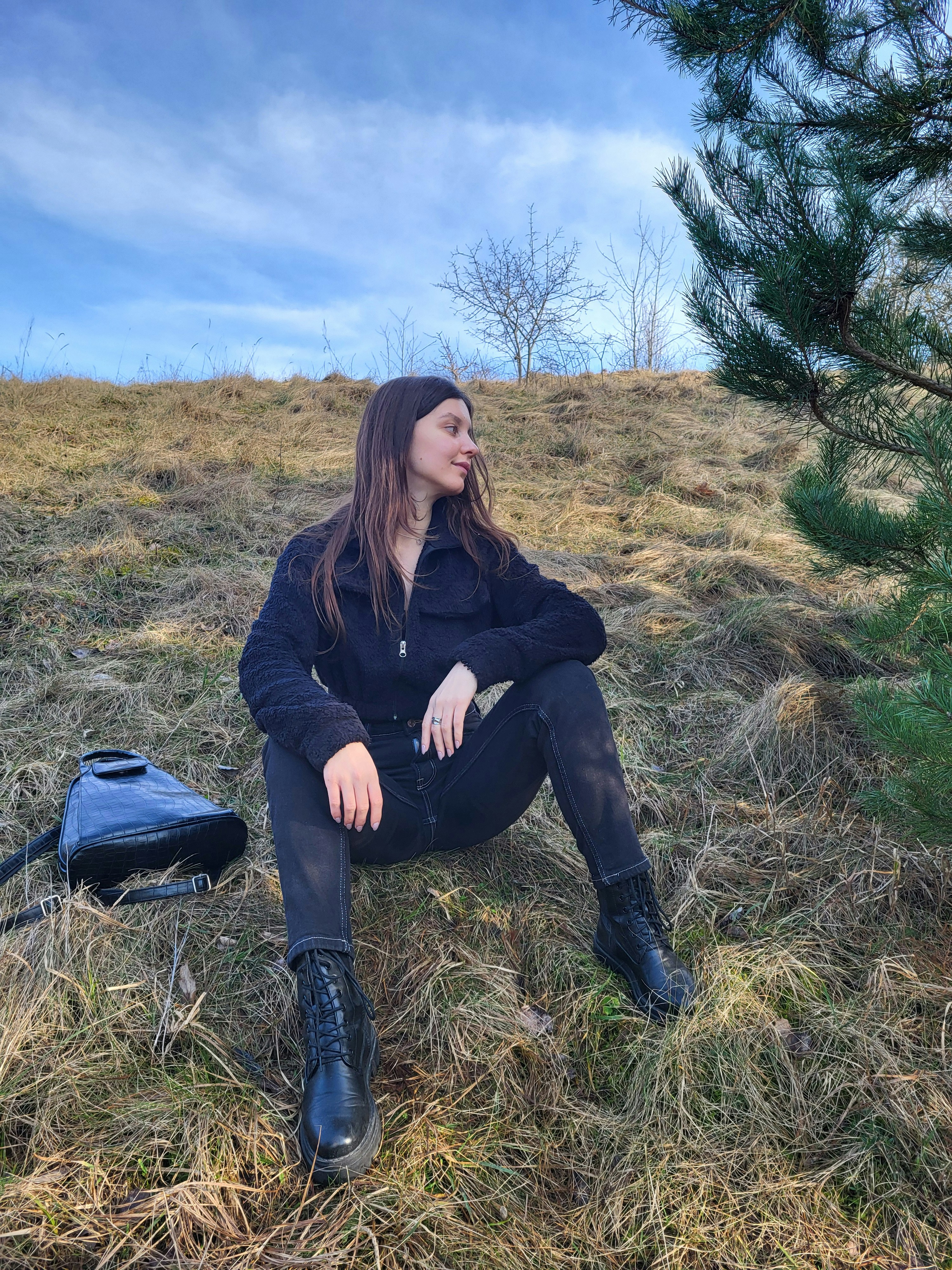 a woman sitting on the ground next to a tree
