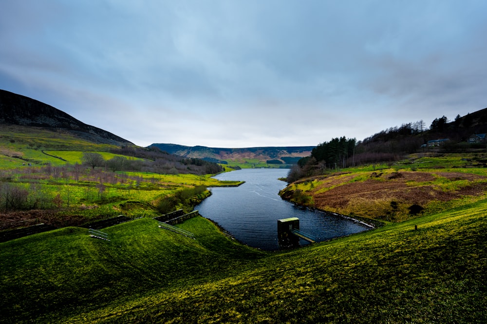 a body of water surrounded by a lush green hillside