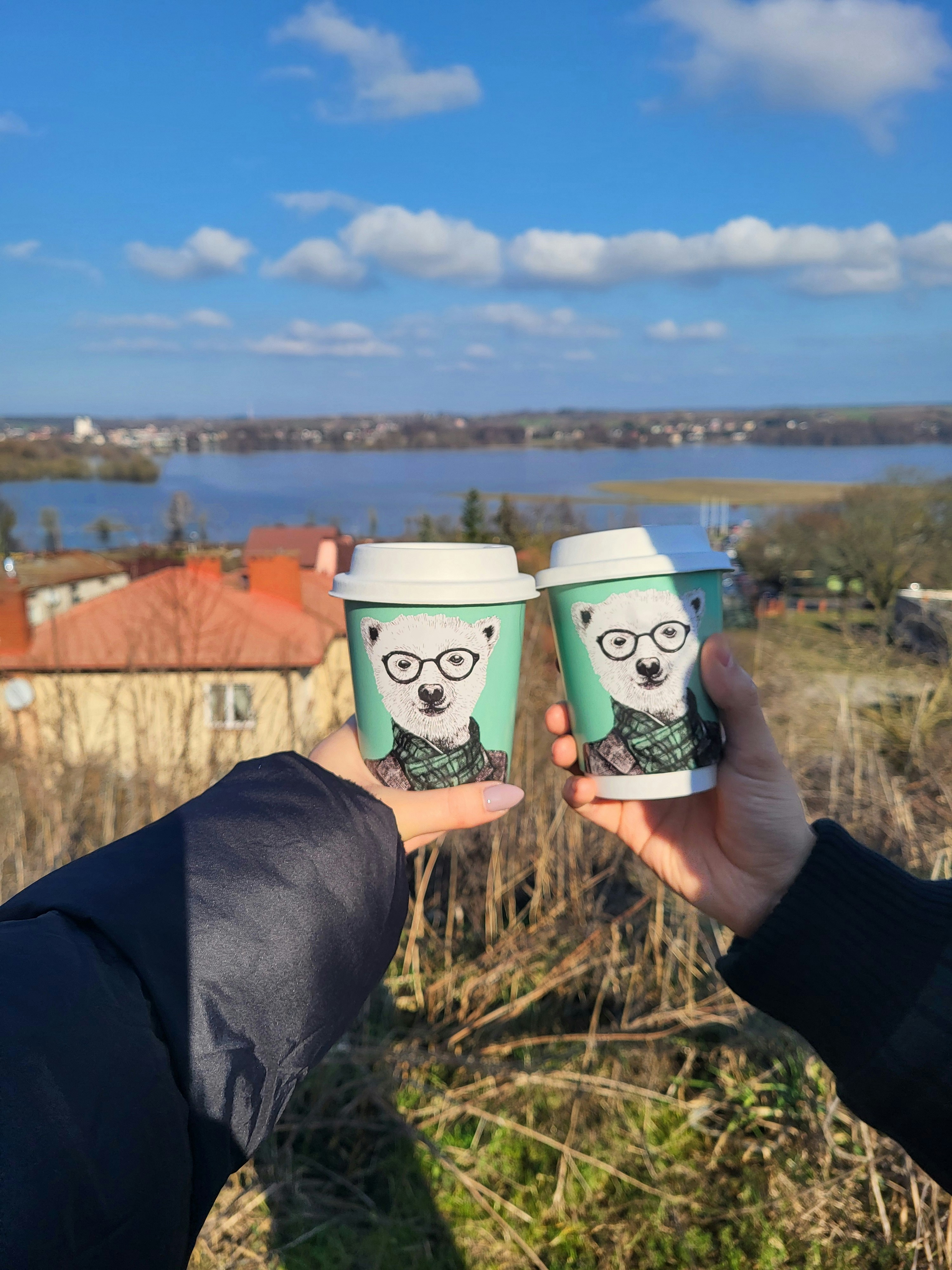 two people holding up cups with a picture of a panda on them