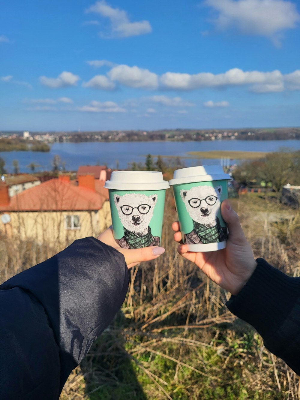 two people holding up cups with a picture of a panda on them