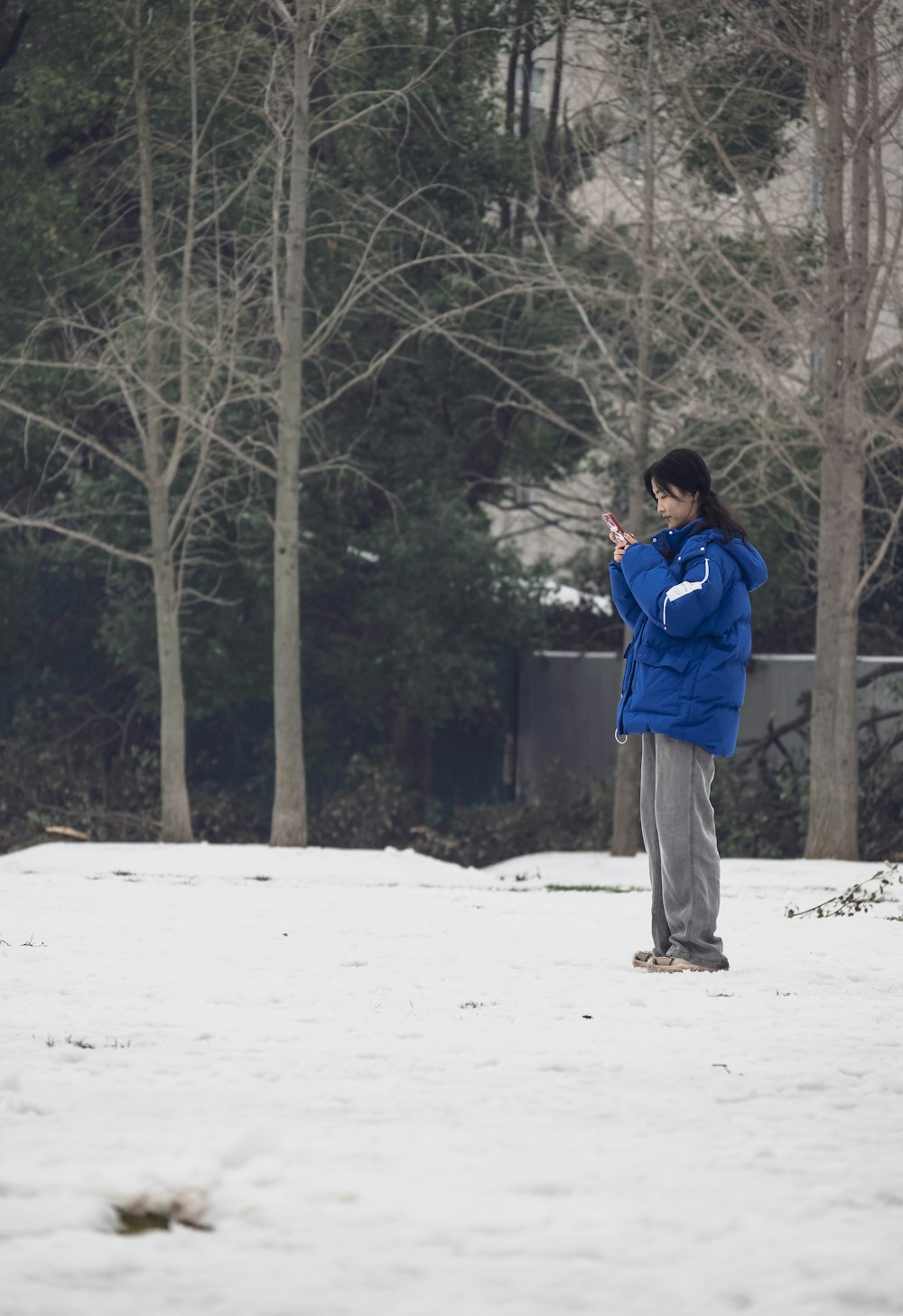 a woman in a blue jacket standing in the snow