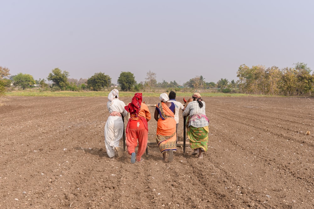 a group of people walking across a dirt field