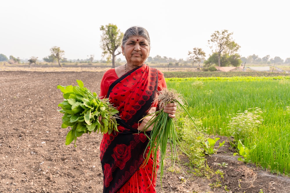 a woman standing in a field holding a bundle of plants