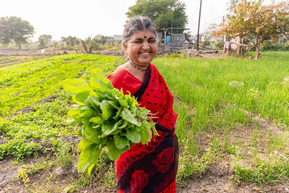 a woman standing in a field holding a plant