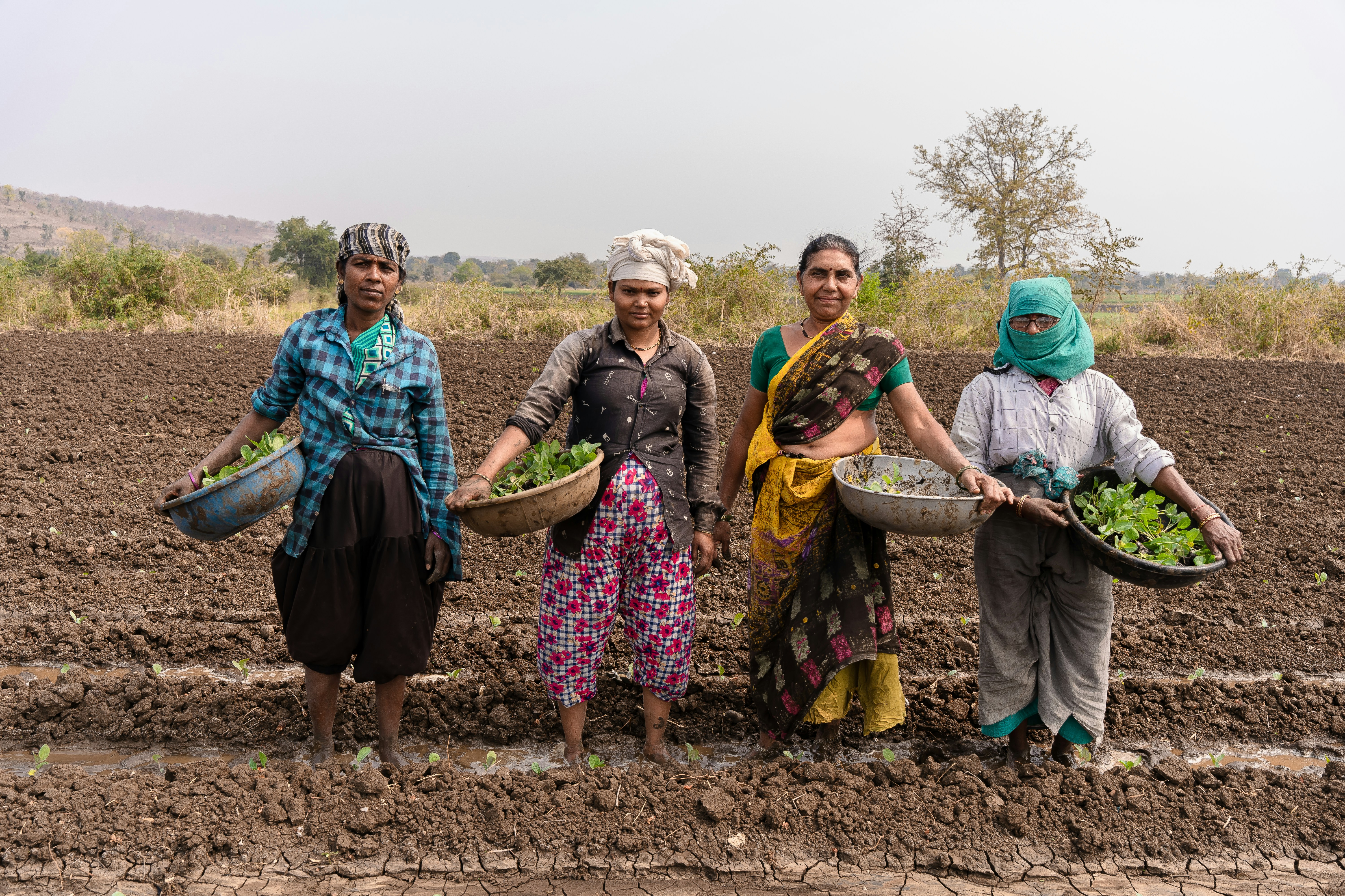 a group of women standing in a muddy field