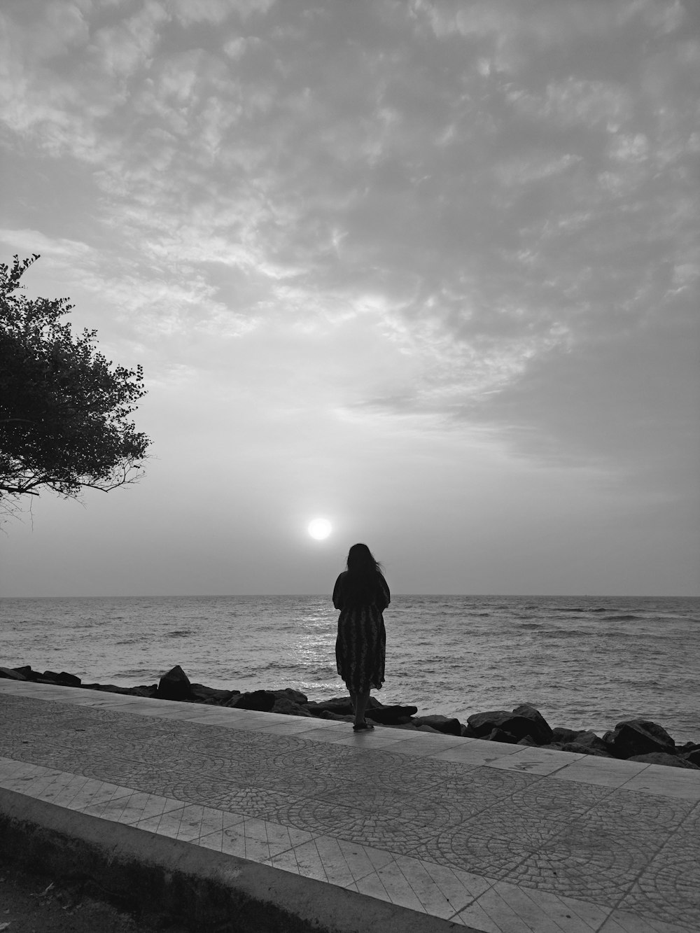 a person standing on the side of a road near the ocean