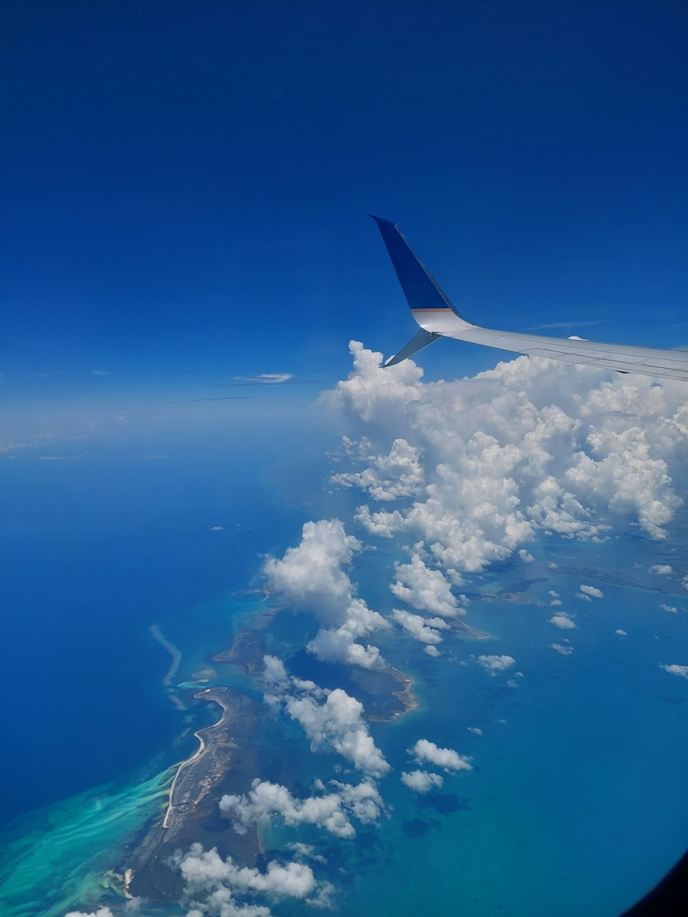 a view of the wing of an airplane flying over the ocean