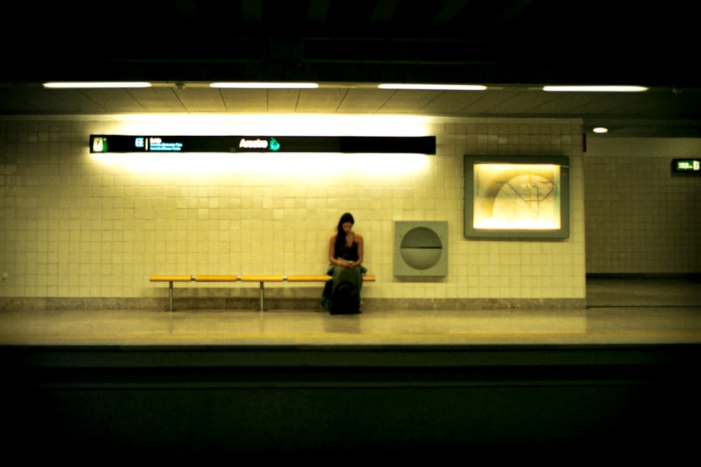 a woman sitting on a bench in a subway station