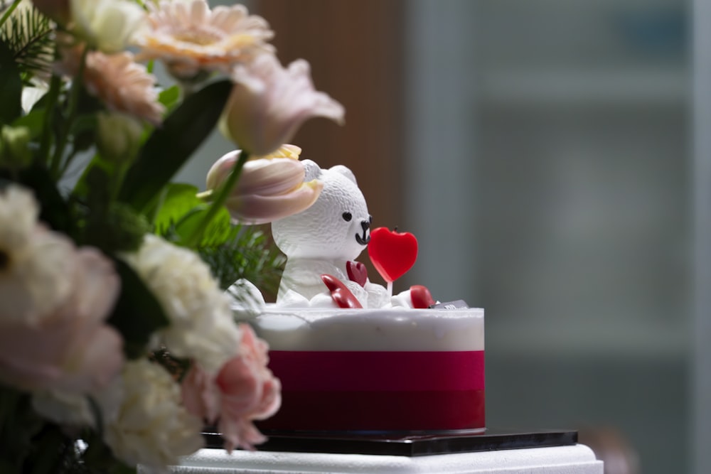 a white teddy bear sitting on top of a cake