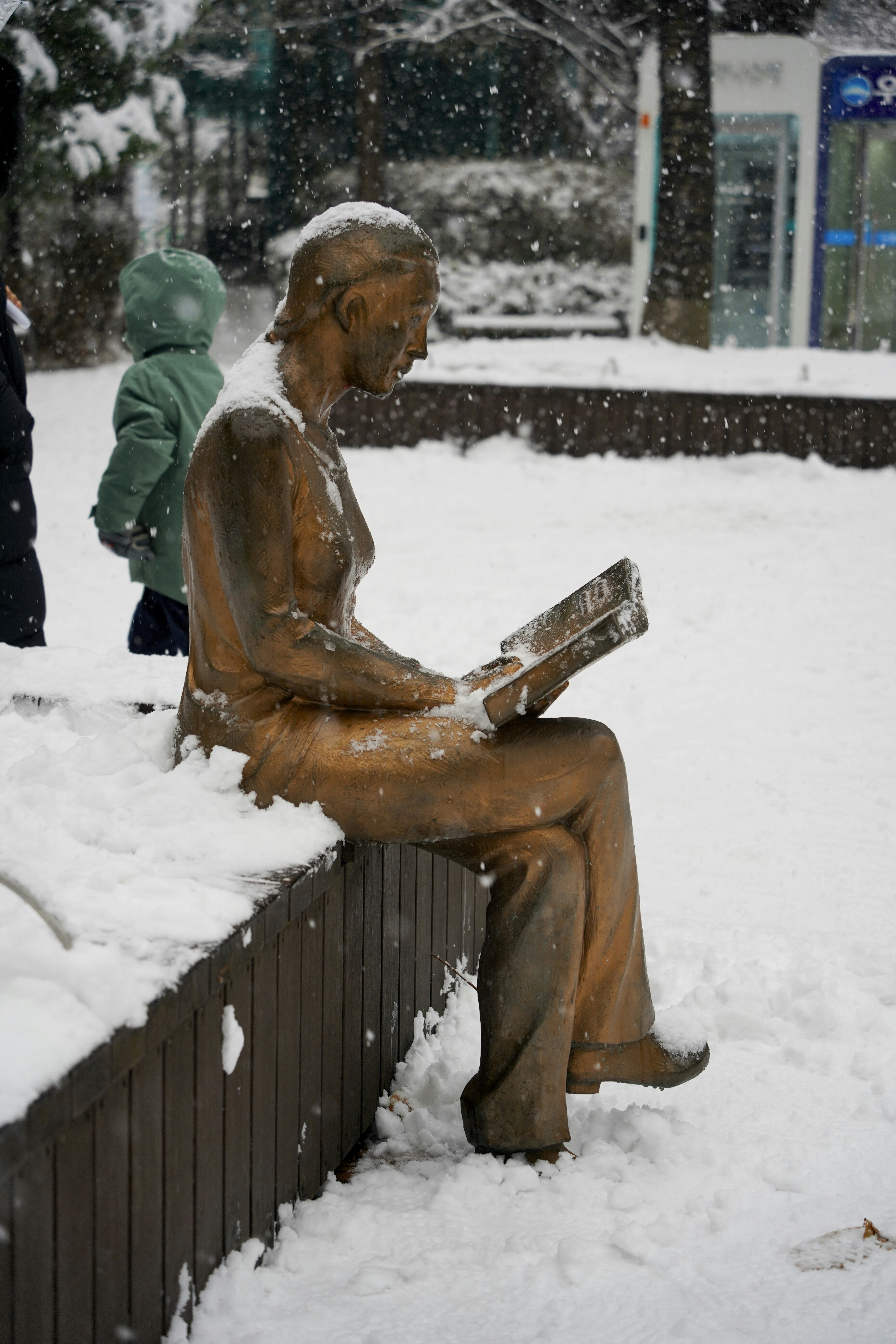 a statue of a man reading a book in the snow