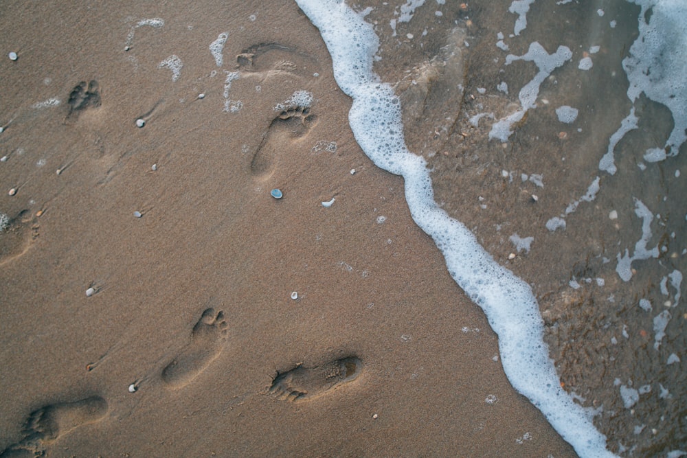 two footprints in the sand next to the ocean