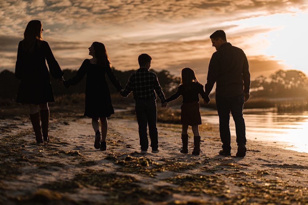 a family walking on the beach at sunset