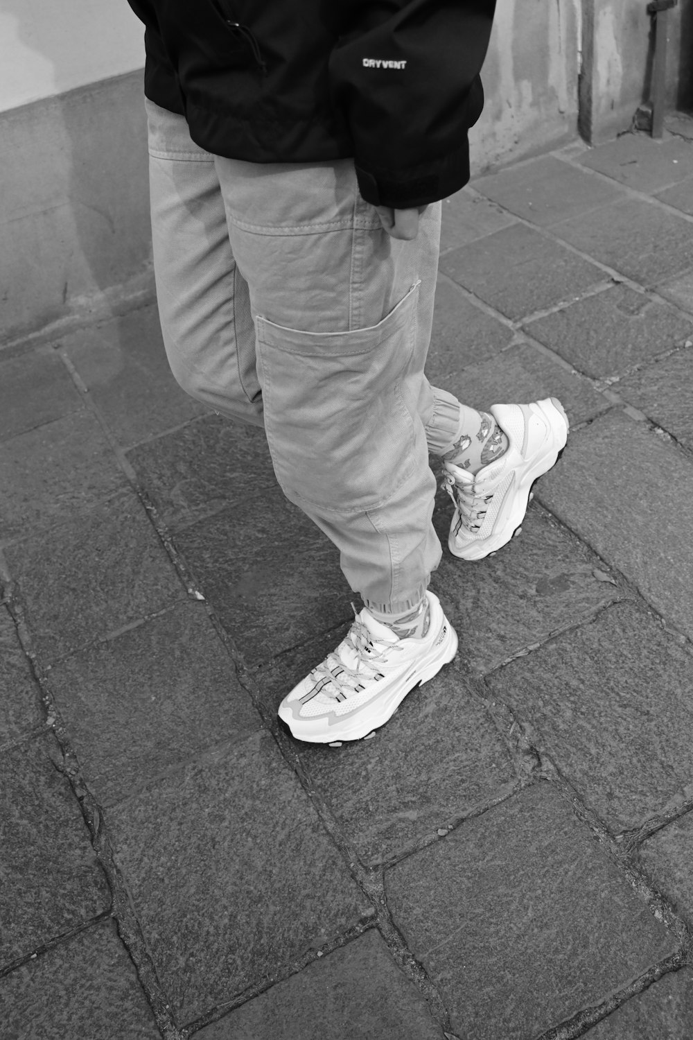 a black and white photo of a person standing on a sidewalk