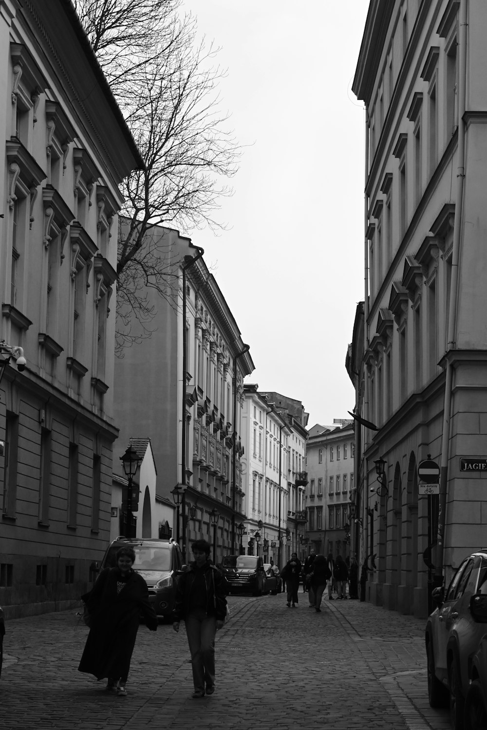 a couple of people walking down a street next to tall buildings