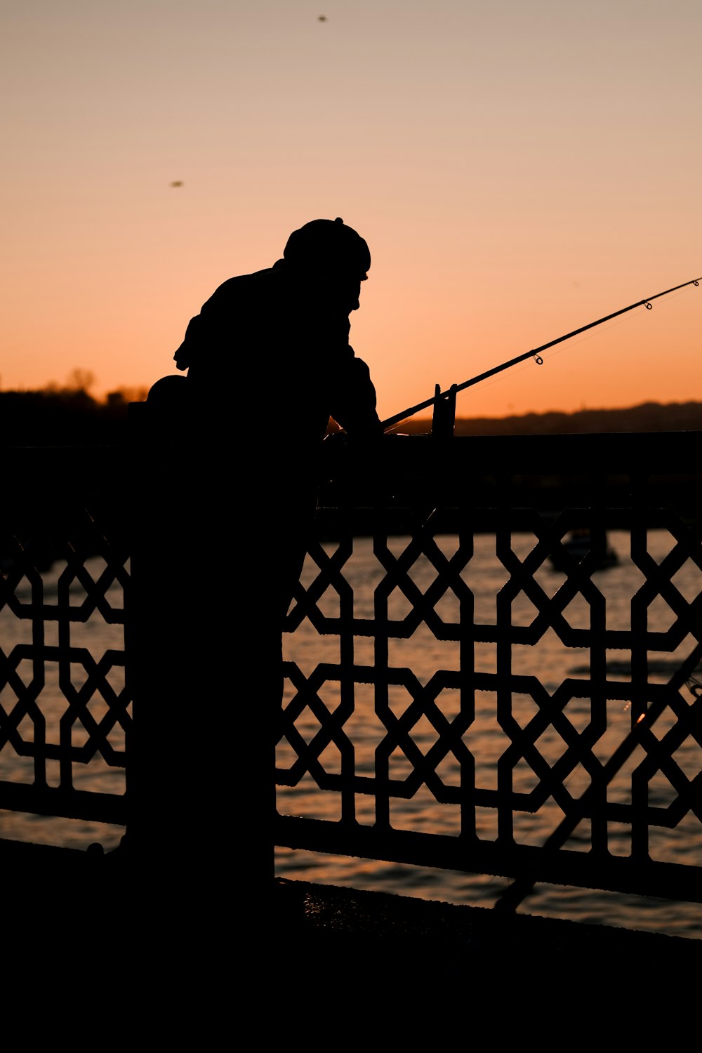 a silhouette of a man fishing at sunset