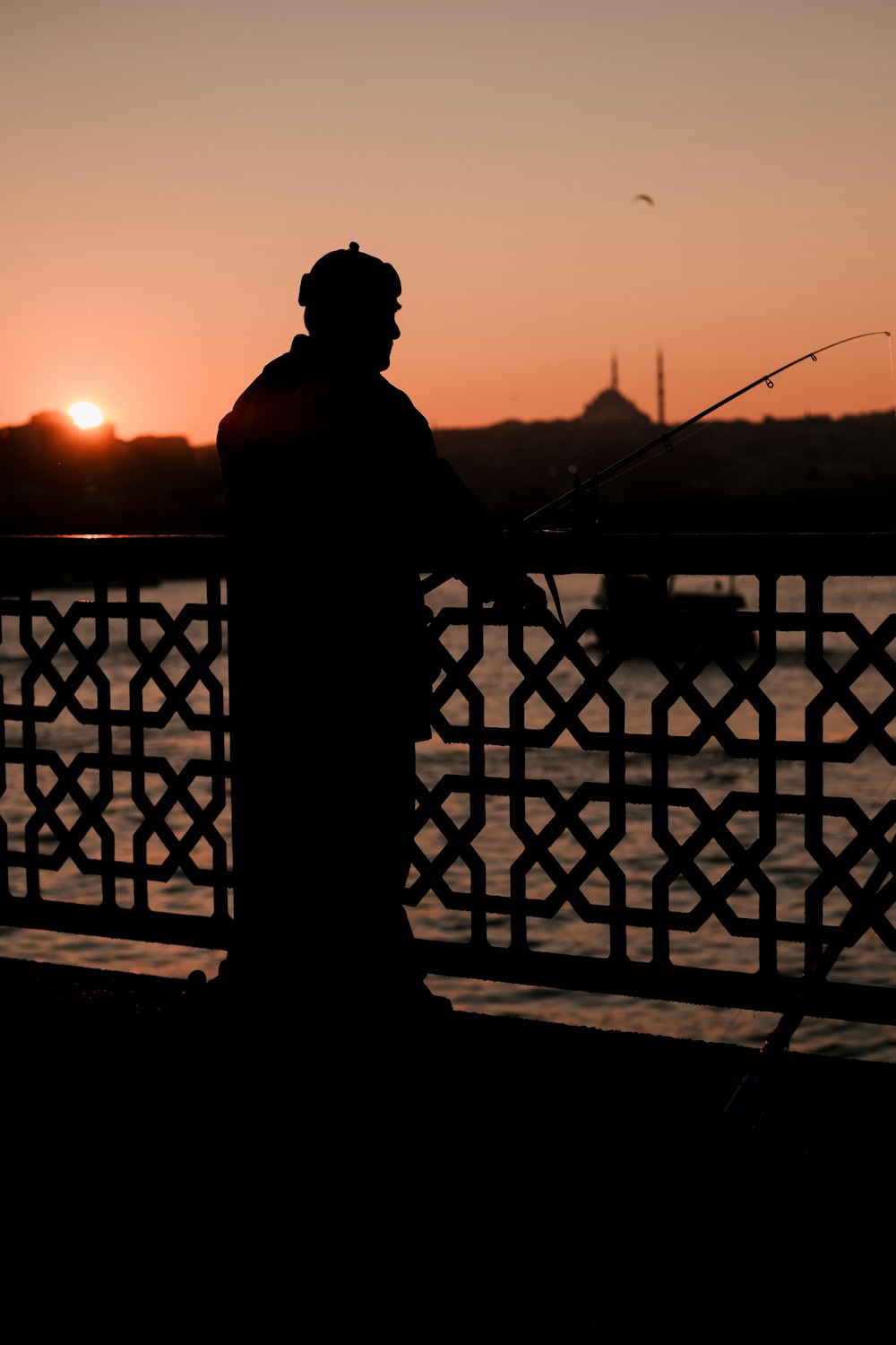 a silhouette of a man fishing at sunset