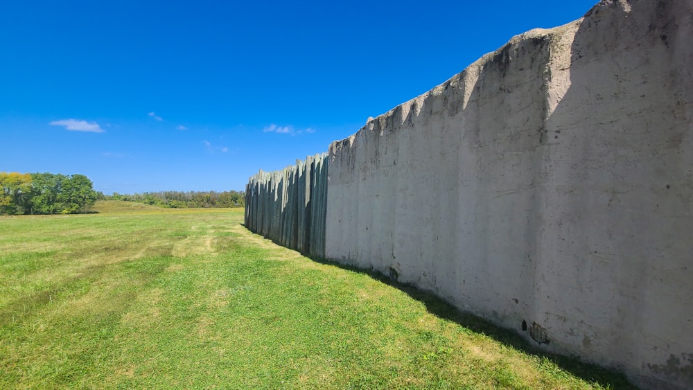 a long concrete wall next to a grassy field