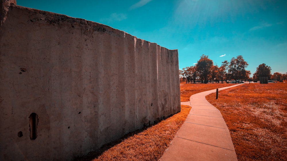 a person walking down a sidewalk next to a cement wall