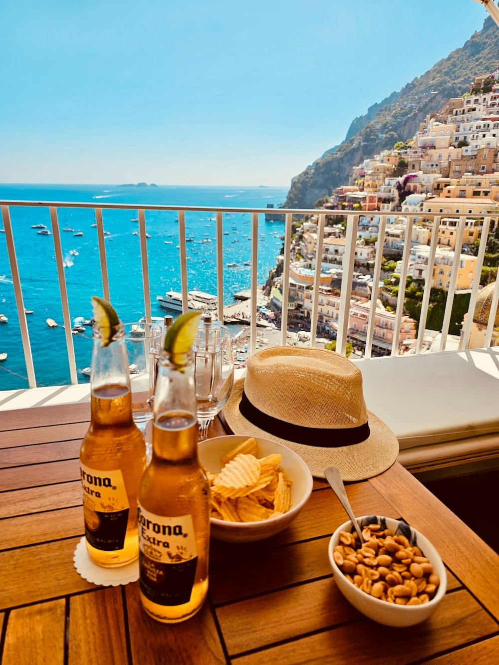 a wooden table topped with bottles of beer and a bowl of food