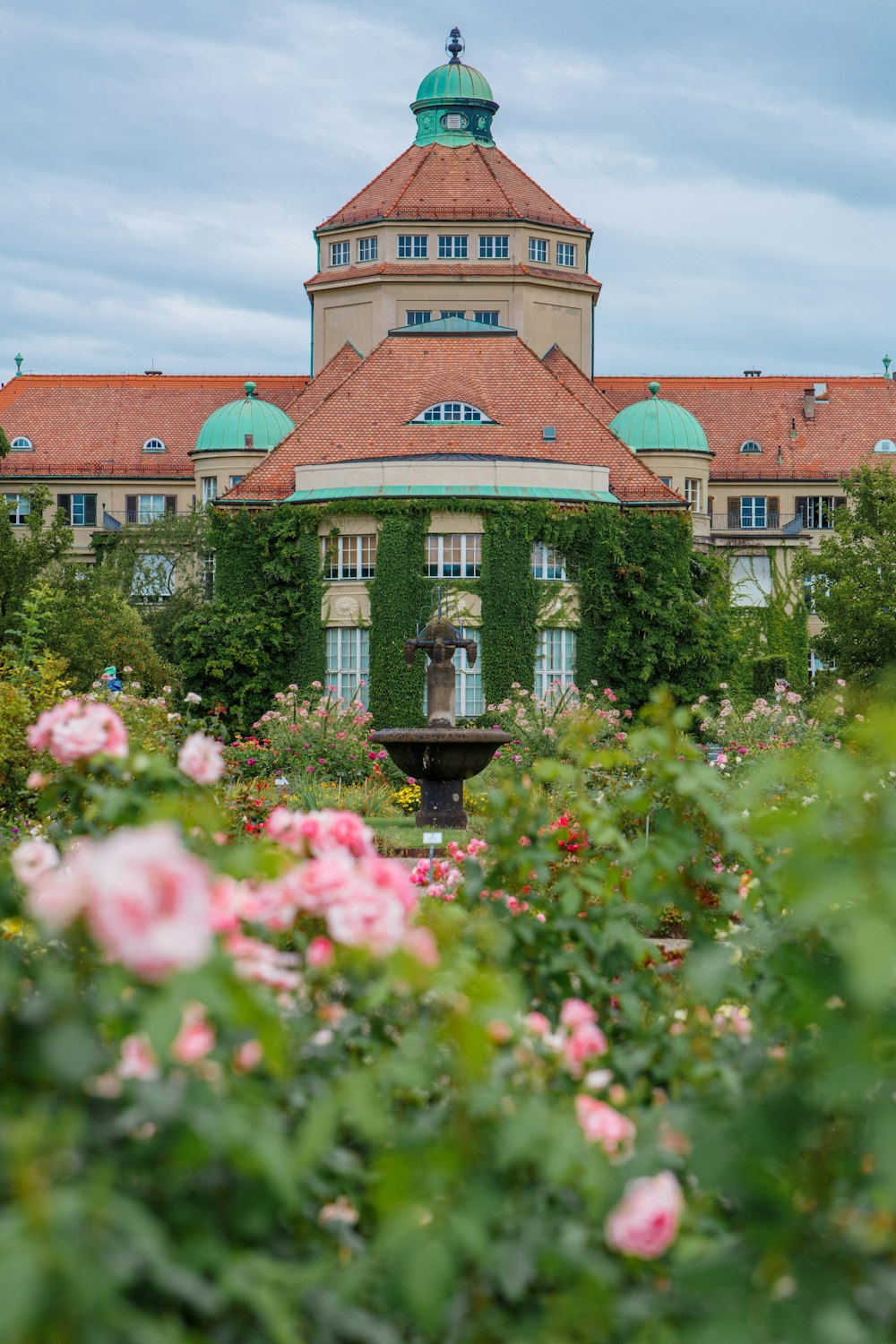 ein Gebäude mit einem Springbrunnen, der von Blumen umgeben ist