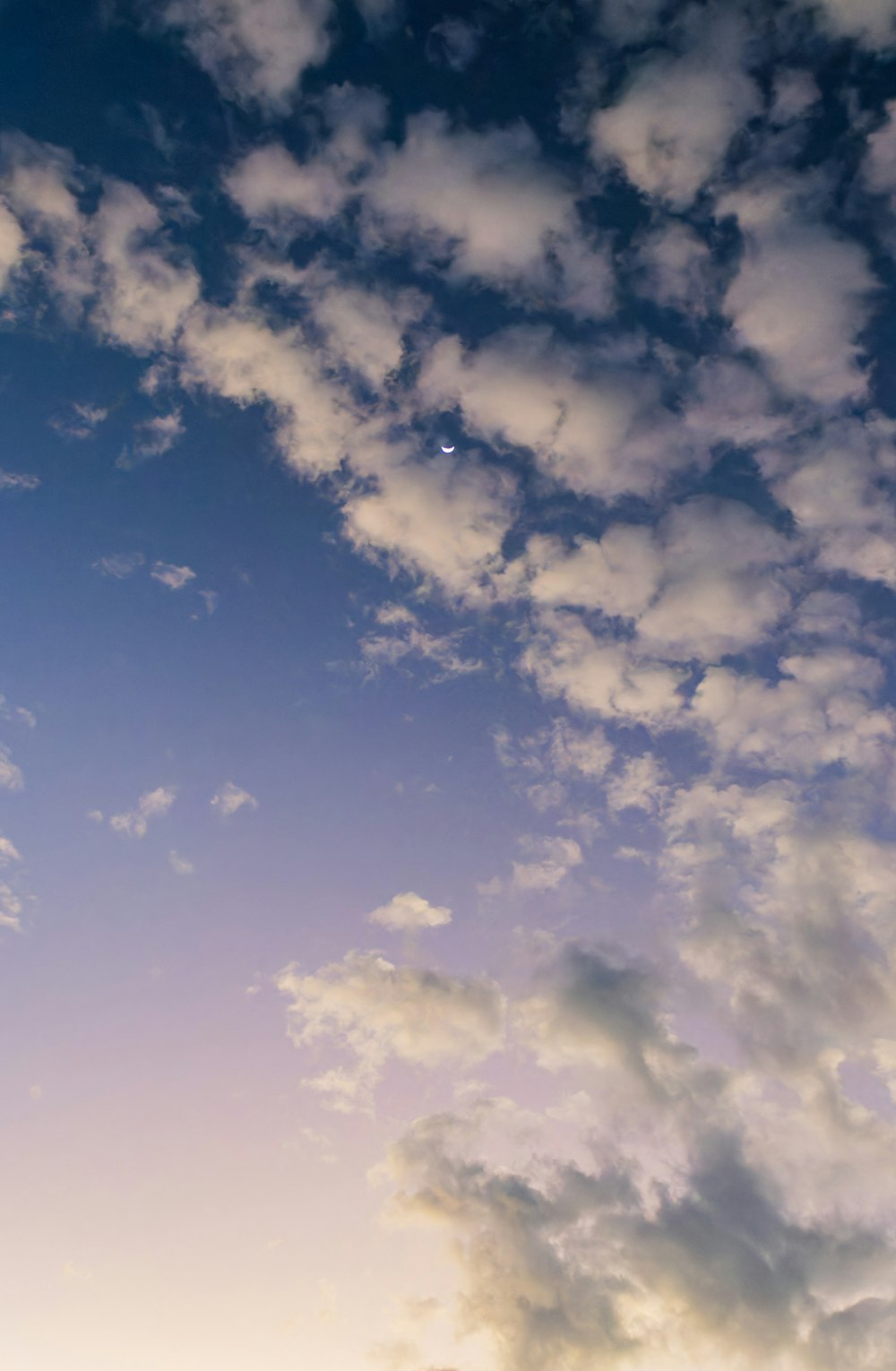 a plane flying through a cloudy blue sky