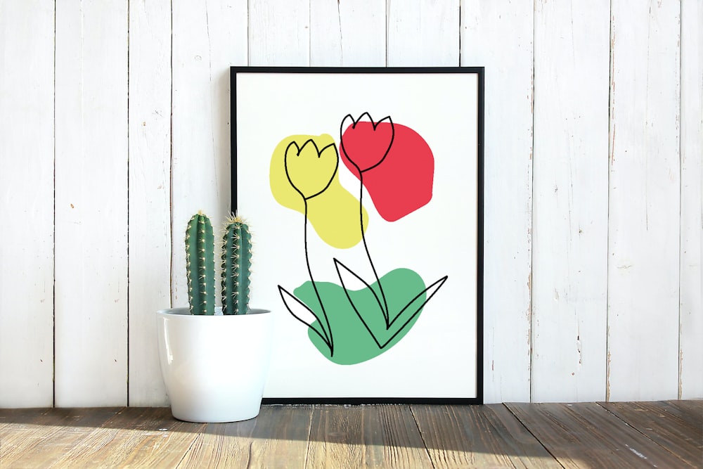 a potted cactus next to a picture of tulips