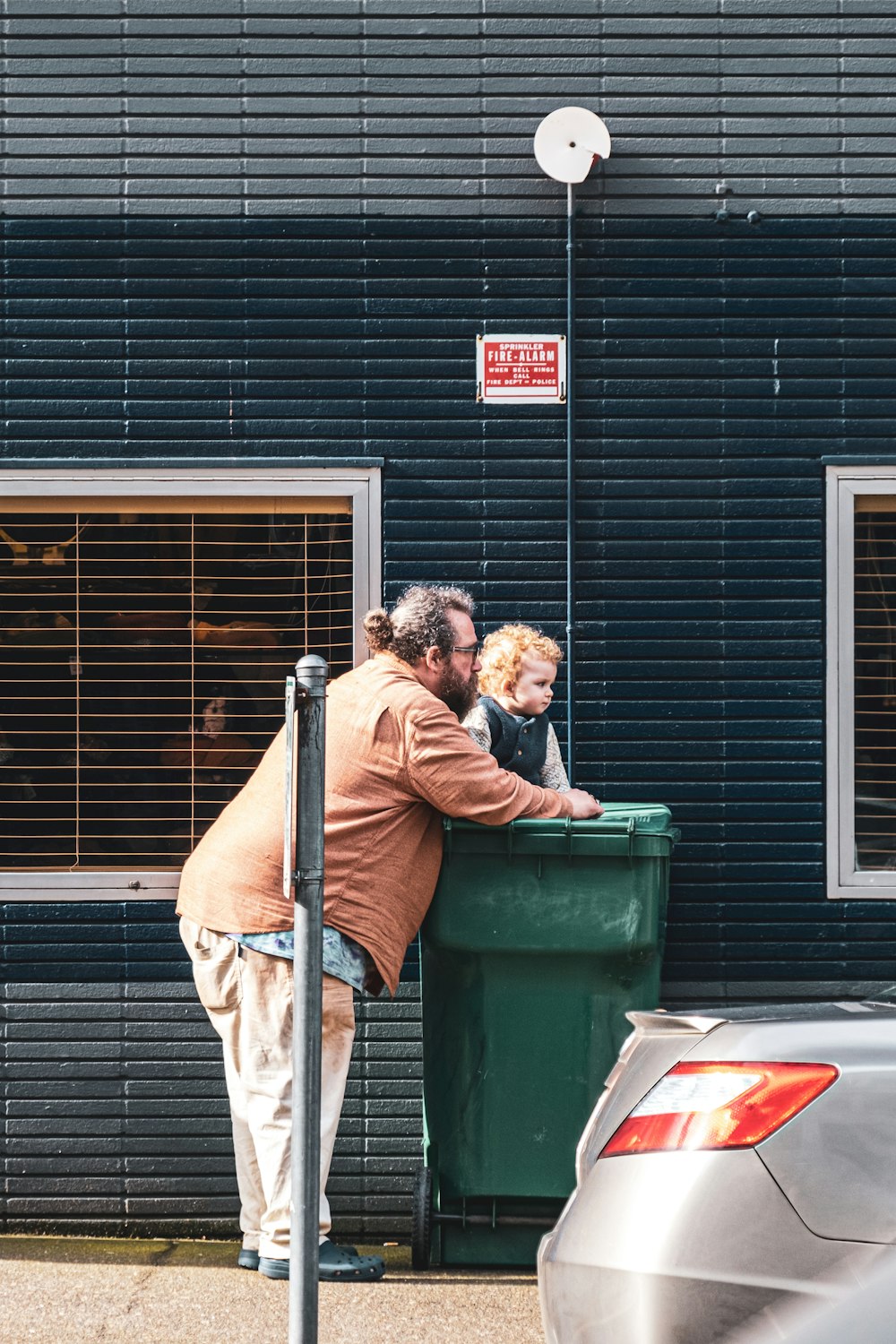 a man standing next to a child near a trash can