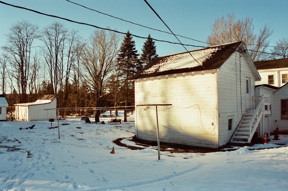 a small white building sitting in the middle of a snow covered field
