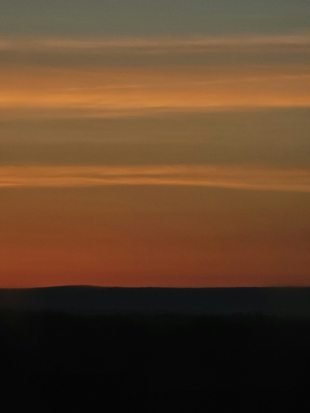 a plane flying in the sky at sunset