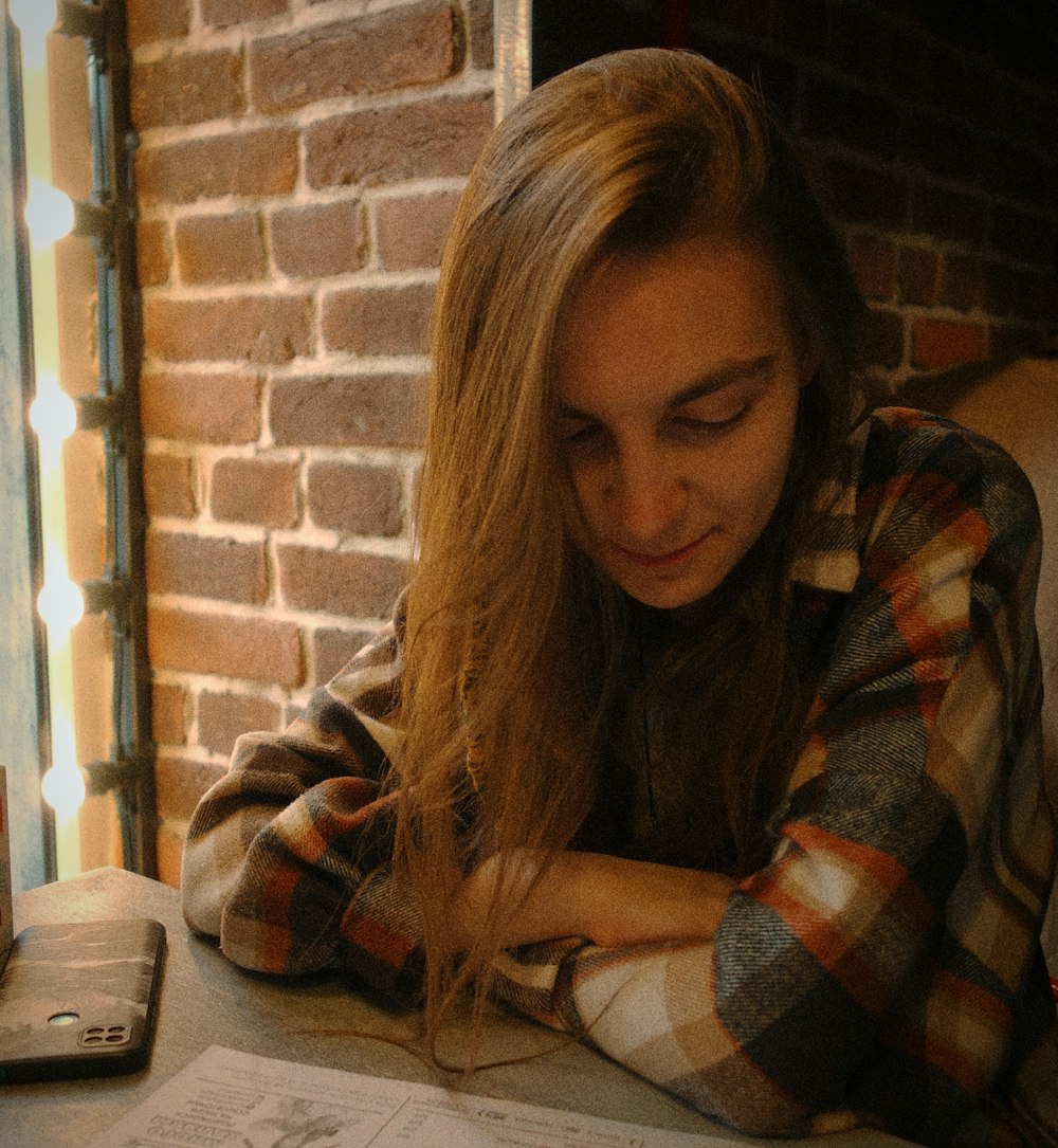 a woman sitting at a table with a cell phone