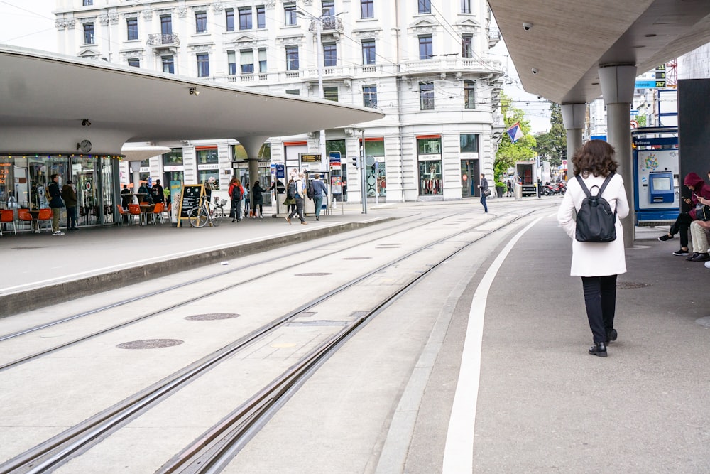 a woman walking down a street next to a train station