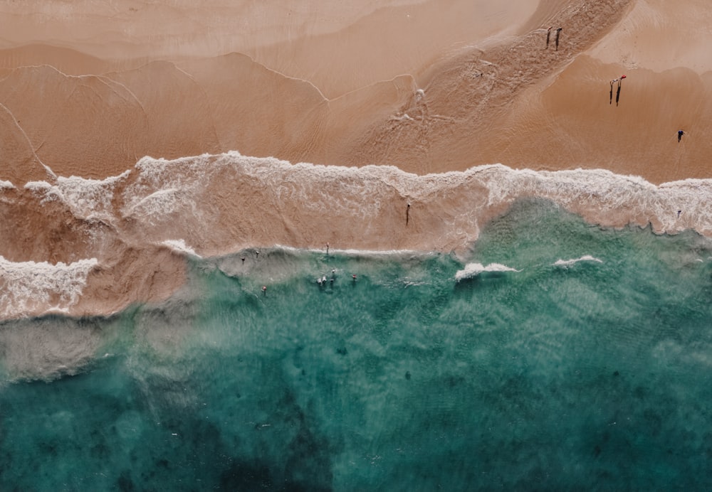 an aerial view of a beach with people walking on it