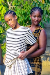 two women standing next to each other in front of a tree