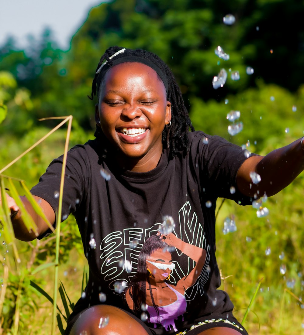 a woman sitting in a field with bubbles of water